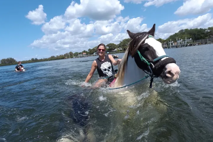 a woman riding a horse in the water