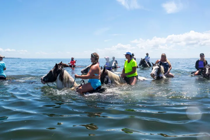 a group of people riding on the back of a boat in the water
